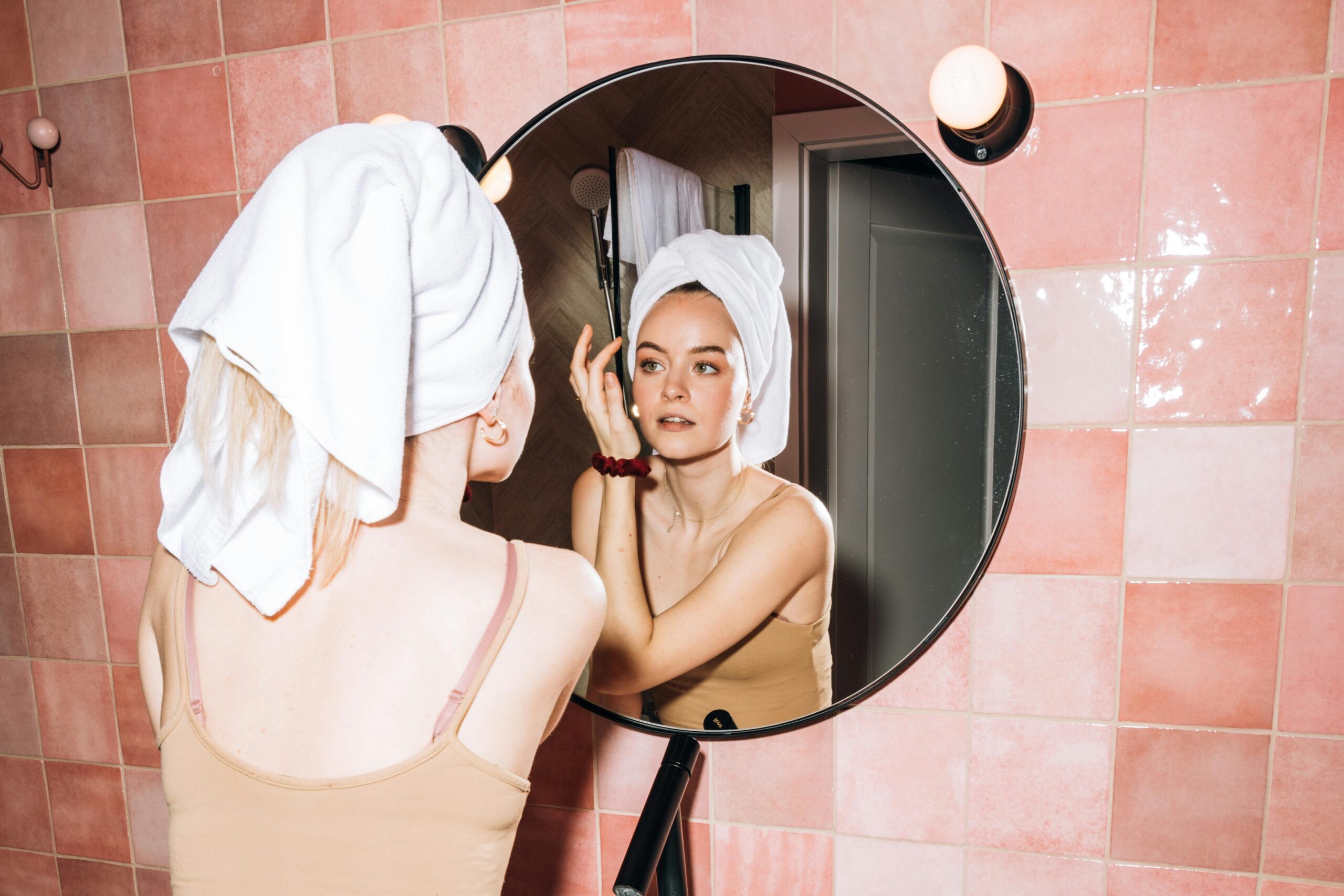 Woman applying green seaweed face mask in bathroom mirror