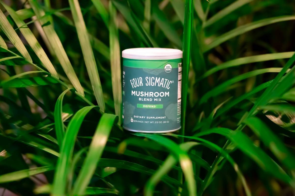 Close-up image showing organic algae capsules on a wooden table with fresh seaweed leaves placed around it.