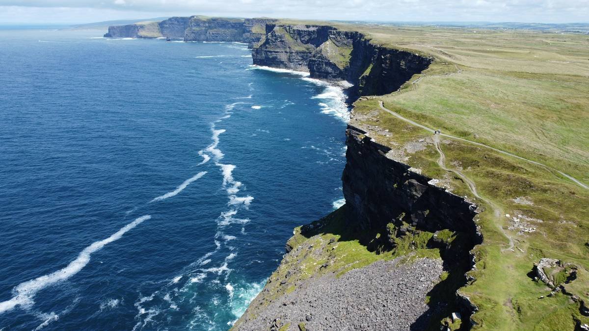 Dramatic cliffs meet the ocean under a cloudy sky.