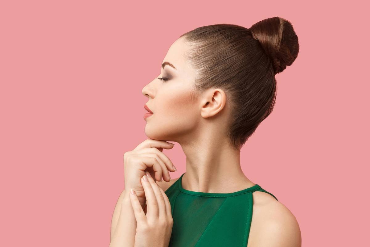A woman in a green dress with her hand on her chin