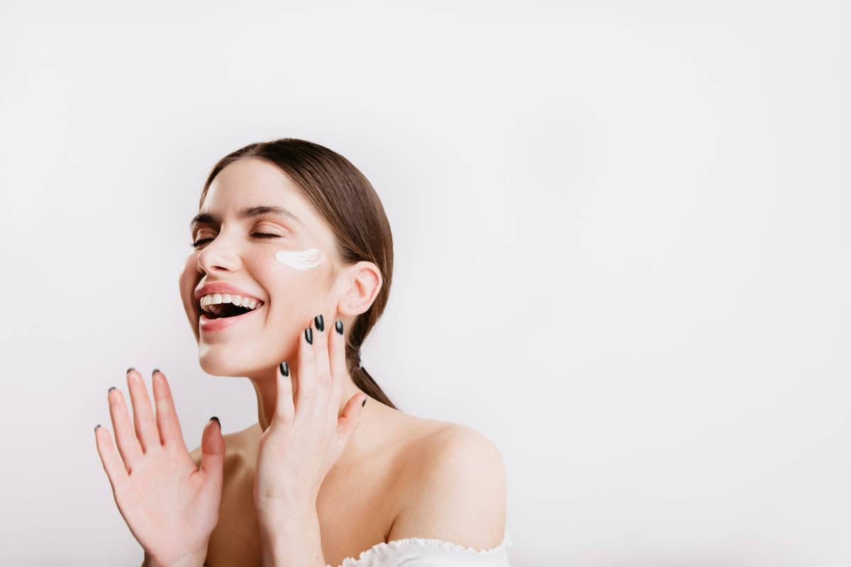 A woman in a white dress smiling and touching her face