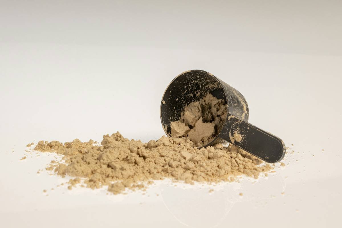 Chocolate protein powder and scoop, gym nutrition and muscle recovery