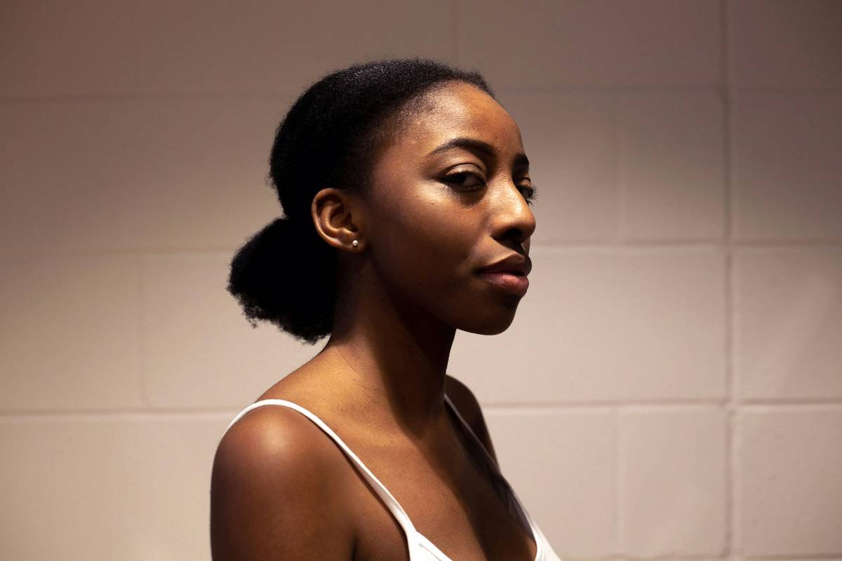 a woman in a white tank top standing in front of a wall