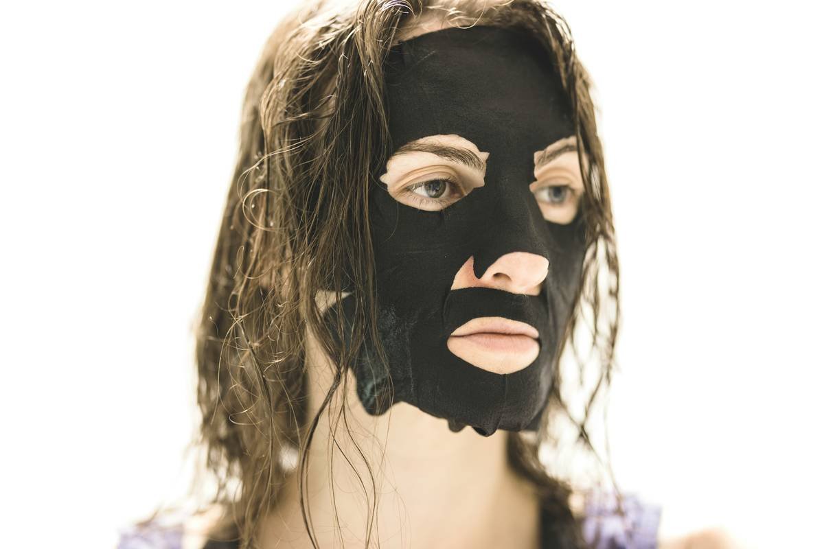 Woman applying a green skin mask seaweed facial at home with calm expression
